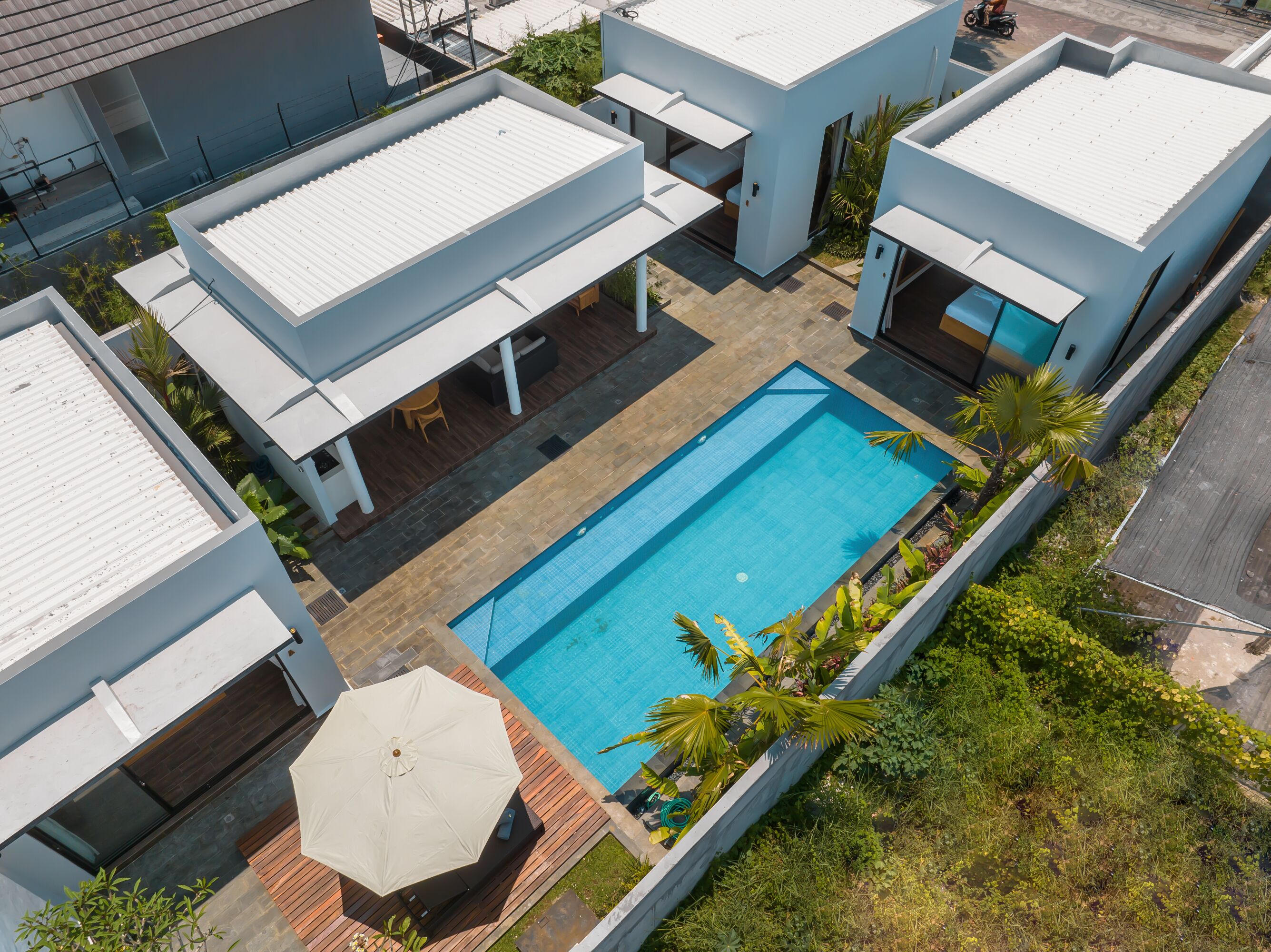 A modern residential complex with a central swimming pool, surrounded by patios and covered seating areas.