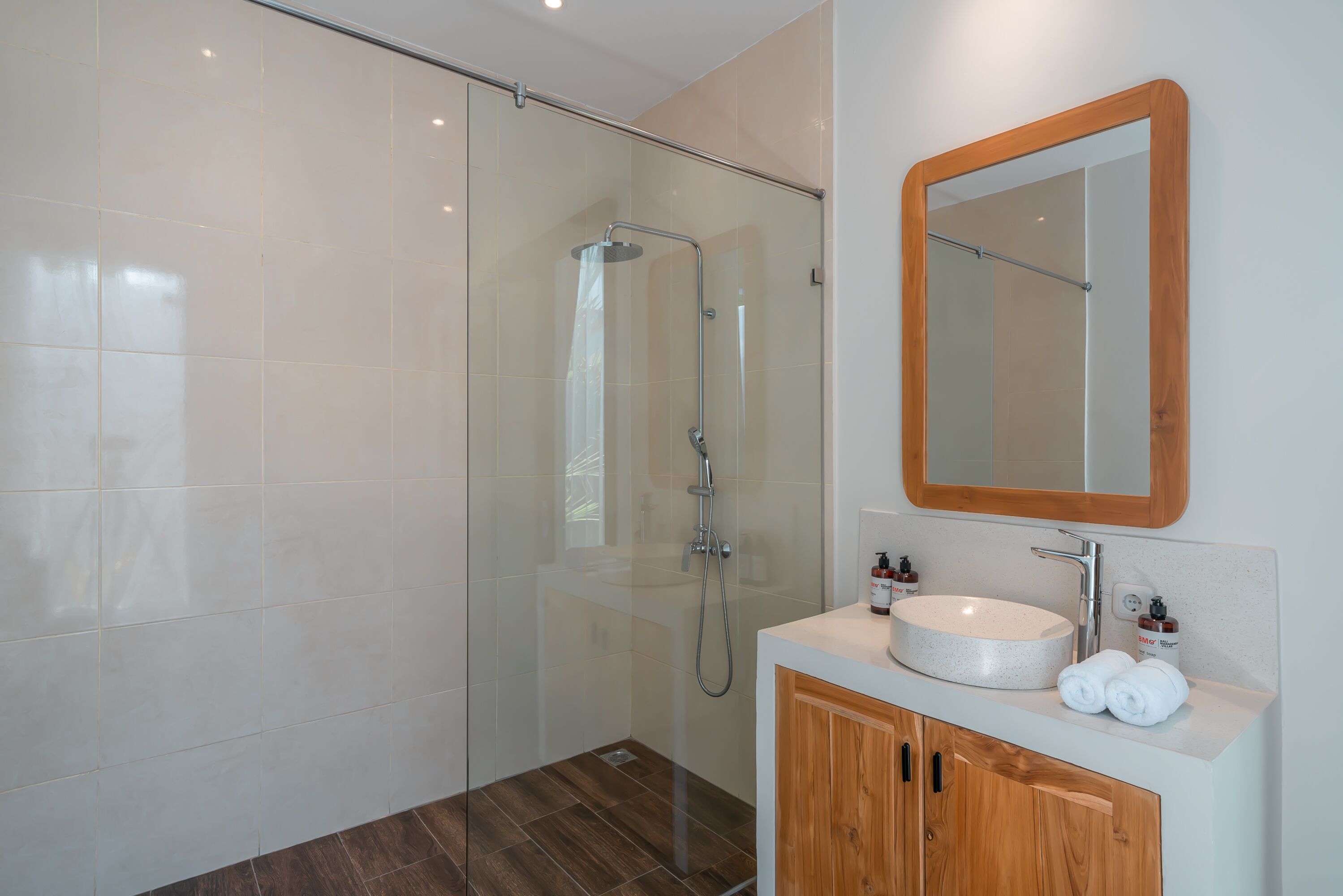 Un bagno moderno con doccia vetrata, un mobile bagno in legno con lavandino e uno specchio.