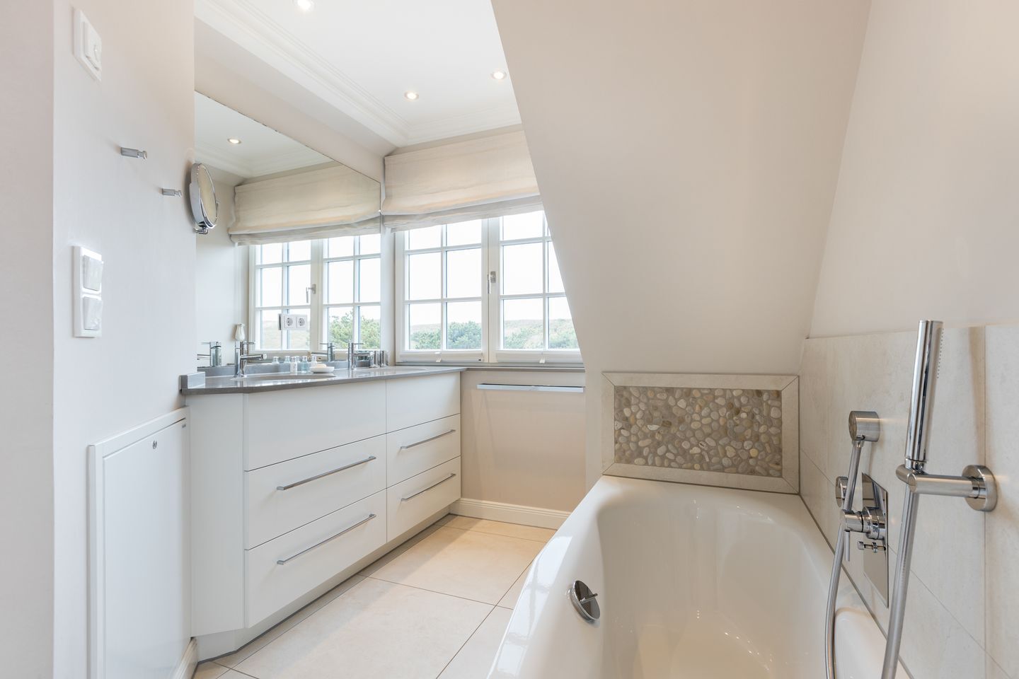 Een moderne badkamer met een badkuip, douche en raam.