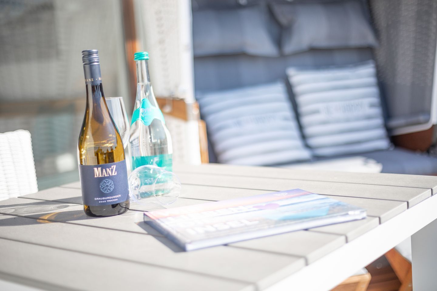 A table with a bottle of wine, a water bottle, and a magazine.