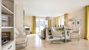Una sala de estar moderna con comedor, que incluye un sofá, un televisor y una mesa de comedor con sillas.