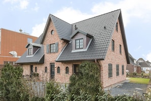 A two-story house with a steeply pitched roof, brick construction, and multiple windows. - Strân Hüs 2 - Luxus-mittel-hausteil in Unmittelbarer Strand- und Meeresnähe Gelegen (Sylt)