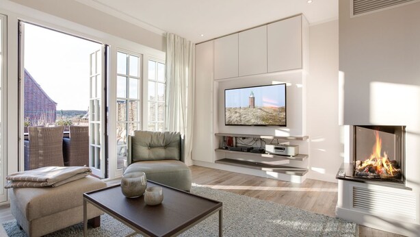 Un salon moderne comprenant un canapé, une table basse, une cheminée, un téléviseur et une grande fenêtre donnant sur l’extérieur.