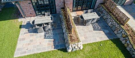 A patio area with stone flooring, a wooden table, and chairs.