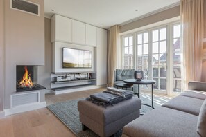 Un salon moderne doté d’une cheminée, d’un téléviseur à écran plat, d’un canapé et d’un coin repas avec une table et des chaises.