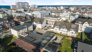 A residential area with a mix of modern and traditional houses, a parking lot, and a view of the sea. - Nette-star, App. 14 - Einmalige Lage. Fantastischer Wellnessbereich. Viel Platz und Stil für Zwei (Sylt)