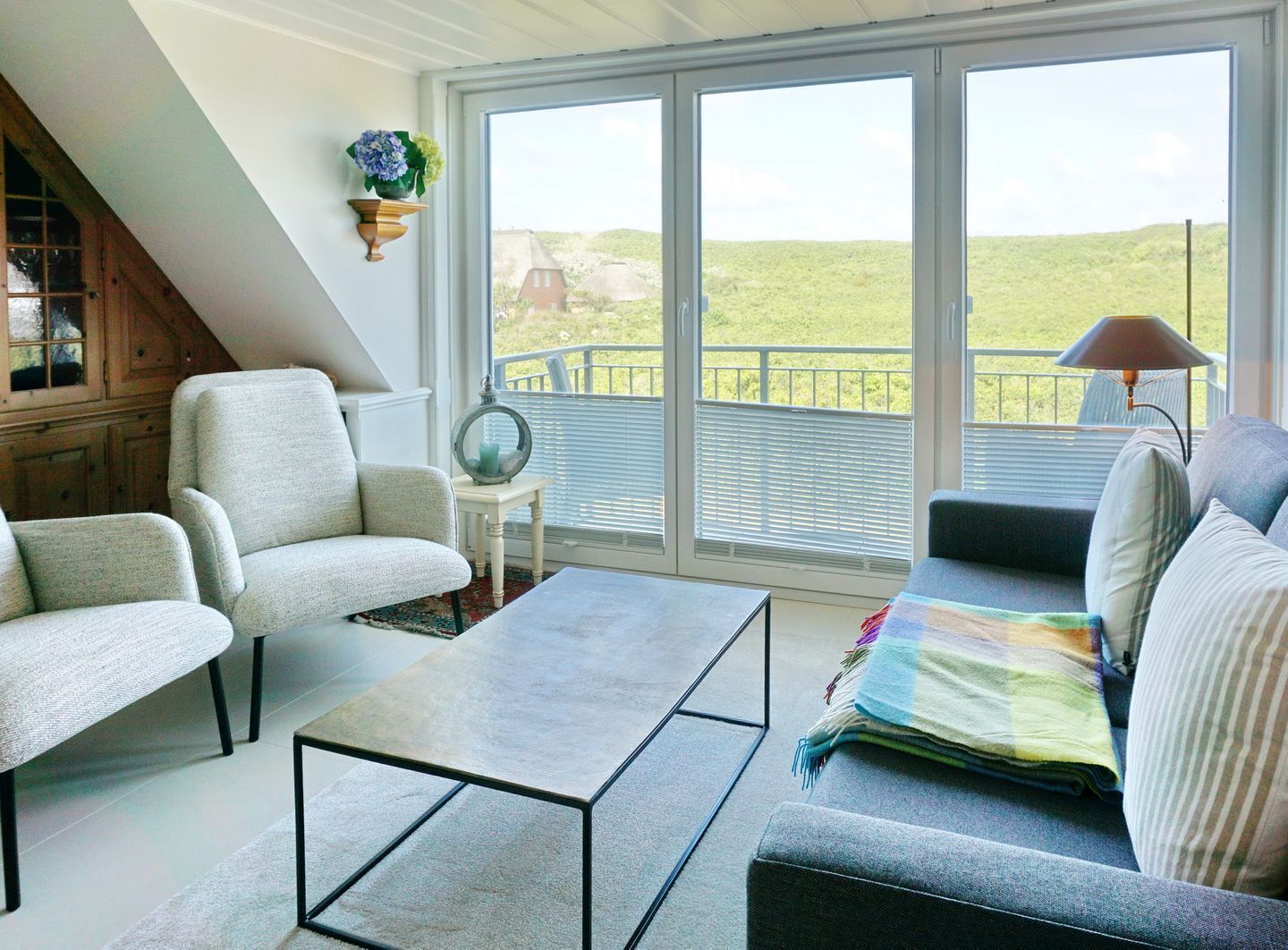 A spacious living area with a view of a green landscape through large sliding glass doors.