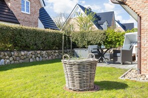 Een tuin met een rieten mand, stenen muur en tuinmeubilair.