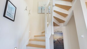 A staircase with wooden steps and white railings, leading to a landing with a framed picture of birds. - Mali - 3-raum Appartement im Ober- und Dachgeschoss mit ca. 75 m² Nutzfläche (Sylt)