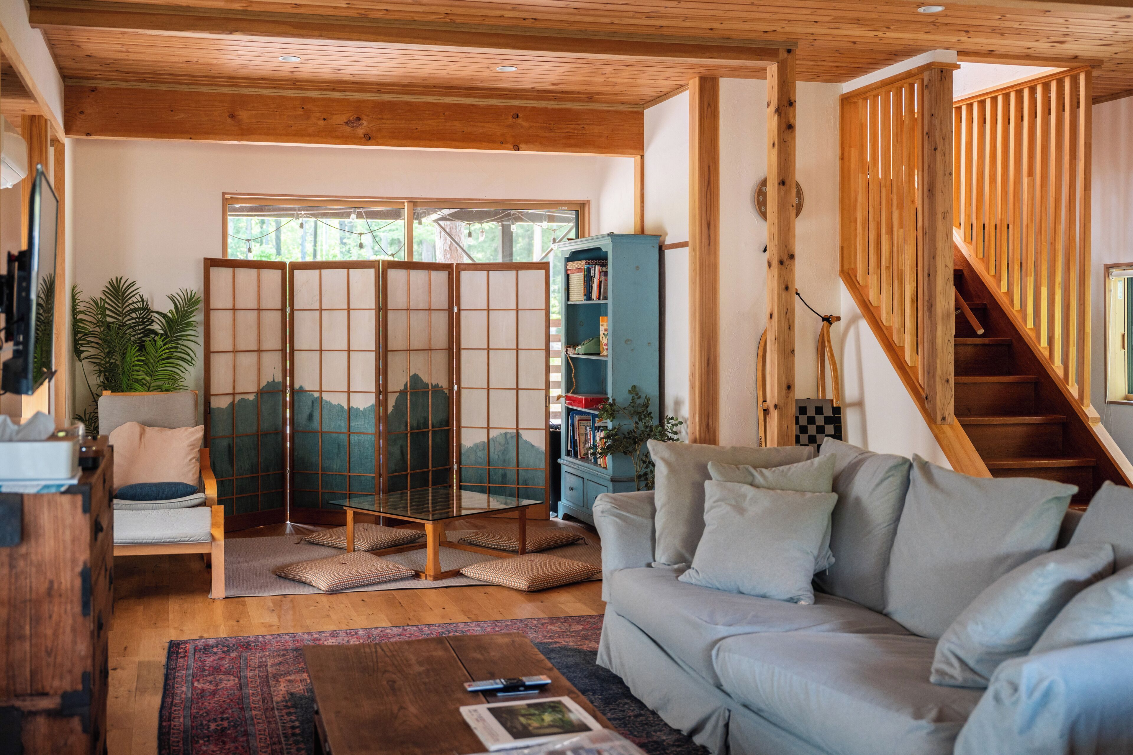 A living room with a sofa, a wooden coffee table, a bookshelf, and a traditional Japanese screen.