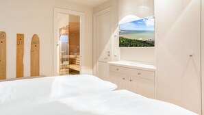 A bedroom with a large bed, a TV mounted on the wall, and a view of the beach through a window. - Anno 1855 - Was für ein Highlight - Sowohl Außen als Auch Innen! (Sylt)