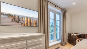 Une chambre avec une grande fenêtre, une table de chevet, un lit et une chaise.