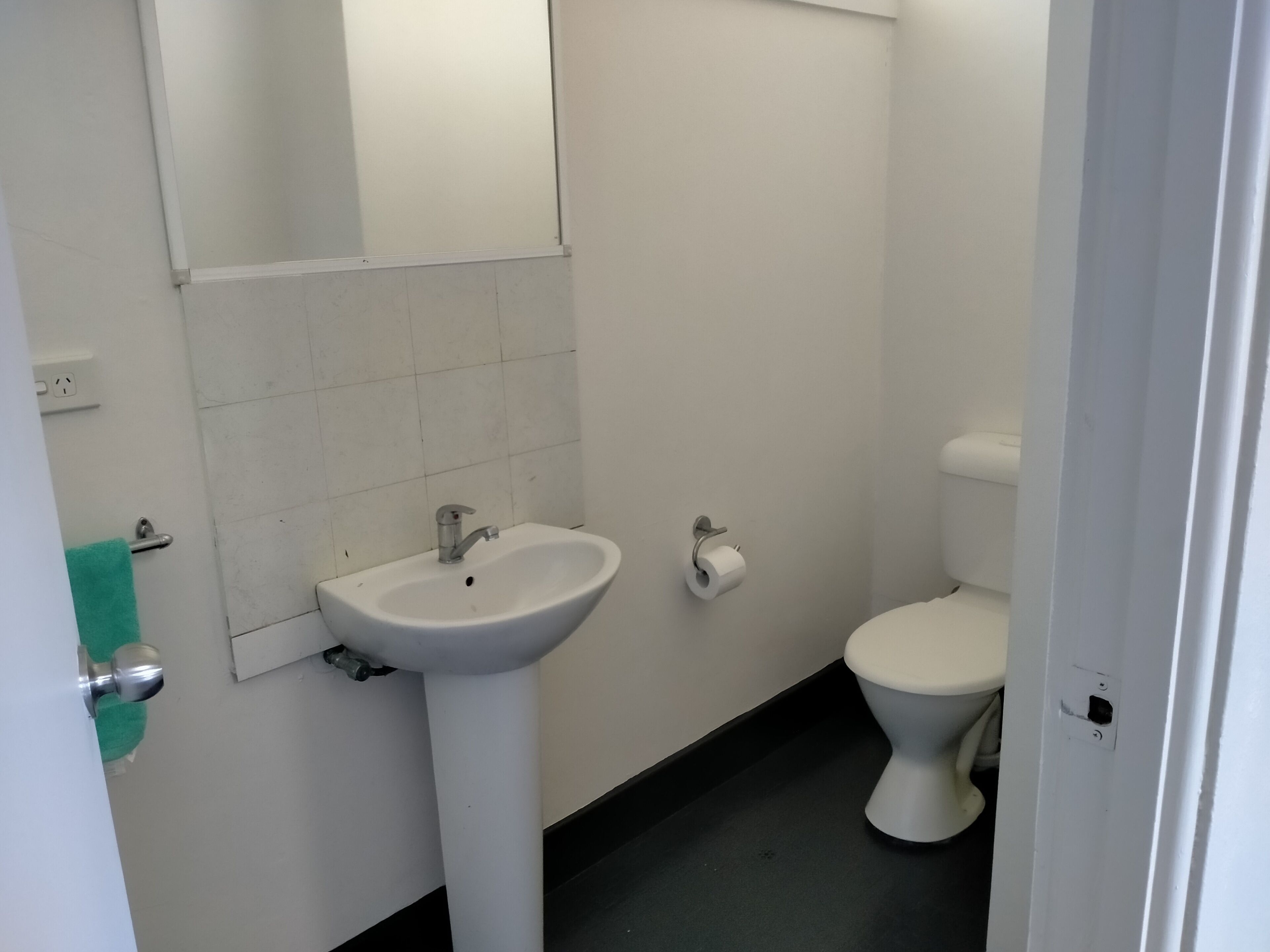 A bathroom with a white sink, toilet, and a mirror.