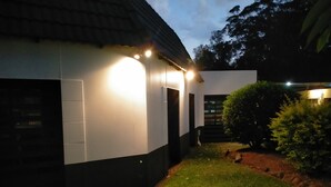 Un bâtiment moderne à l’extérieur blanc, agrémenté de bordures noires, avec une pelouse bien entretenue et un petit jardin orné d’un arbuste.