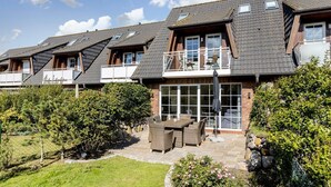 Una hilera de casas modernas con techos inclinados, ventanas amplias y un patio con mobiliario exterior.