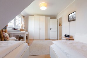 Un dormitorio con dos camas, un escritorio, un armario y un televisor.