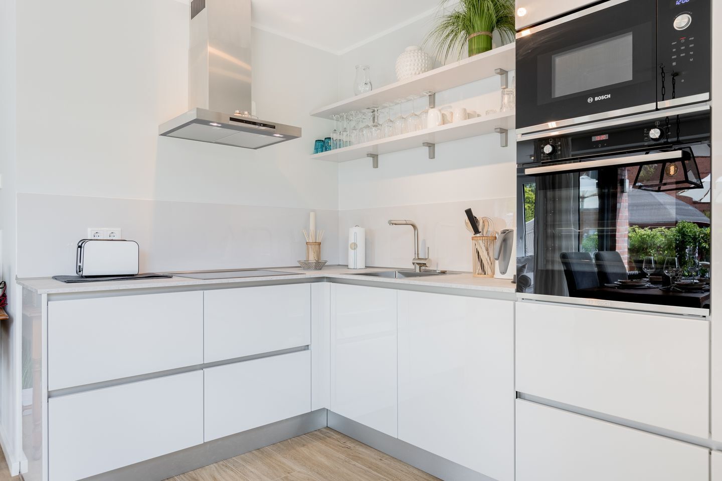 Une cuisine moderne avec des meubles blancs, un four encastré et un grille-pain.
