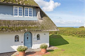A white building with a thatched roof, a blue door, and numbered as 16A.