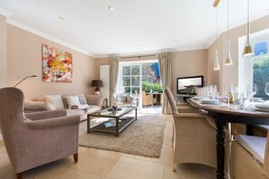 A modern living room with a sofa, coffee table, and dining area set for a meal. - Carlotta - Long Island Style. Ganz Groß (Wenningstedt-Braderup (Sylt))