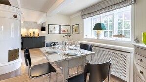 A modern kitchen with a dining area, featuring a large window with a view of greenery, a built-in stove, and a dining table set for six.