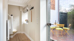 A hallway with a wooden floor, a white door, and a window with a curtain.