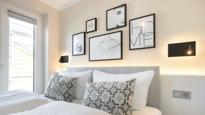 A bedroom with a bed, two patterned pillows, a headboard, and framed artwork on the wall.