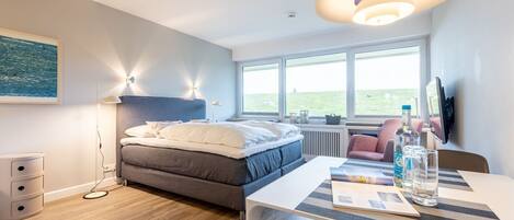 A modern bedroom with a bed, bedside table, and a large window.