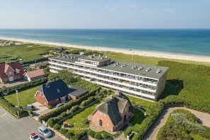 Un hotel grande con varias plantas, vista al mar y zona de estacionamiento.