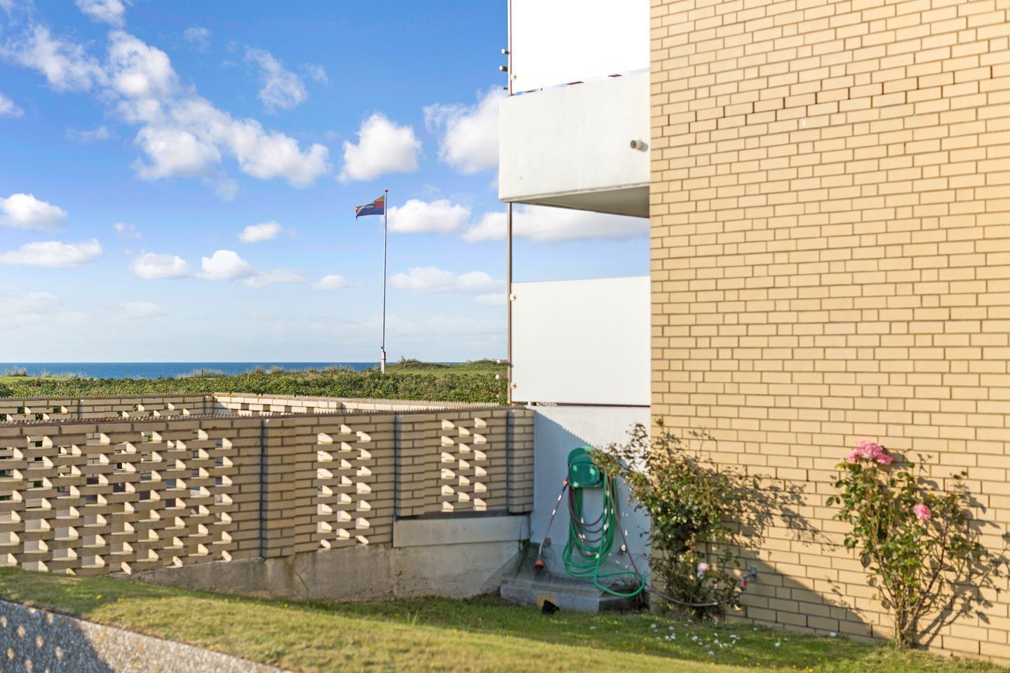 Un edificio de fachada de ladrillo, una bandera en un asta y vista al mar.