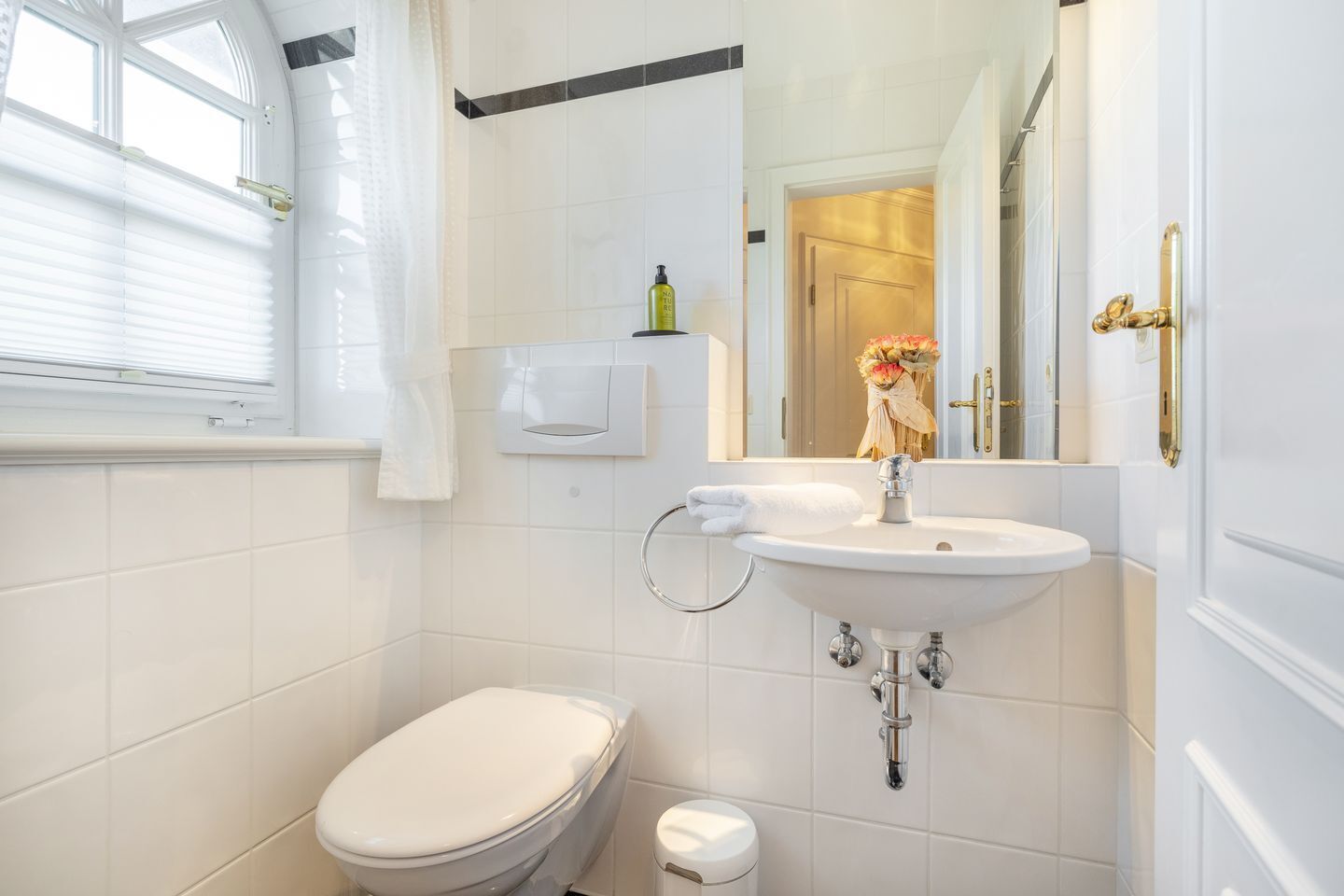 Une petite salle de bain propre, avec des toilettes blanches, un lavabo et un miroir.