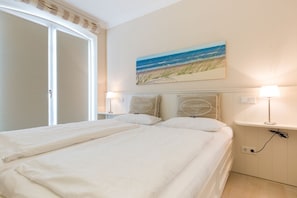 Ein Schlafzimmer mit zwei Betten, einem Strandbild und einem Nachttisch mit Lampe.