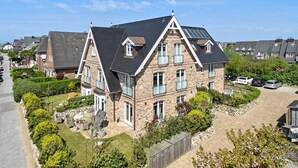 A large, two-story house with a stone facade, multiple windows, and a paved driveway. - Landhaus Berthin-bleeg, App. 5 Strandleben - Top Lage. Beach-style Ausstattung. Viel Platz. Alles (Wenningstedt-Braderup (Sylt))