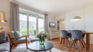 Een moderne woonkamer met een bank, stoelen, een eettafel en een televisie.