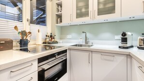 Een moderne keuken met witte kastjes, een roestvrijstalen spoelbak en een ingebouwde oven.