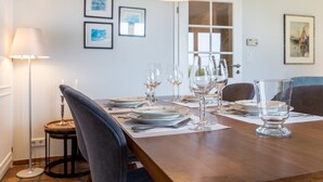 Een eetgedeelte met een houten tafel voor vier personen, omringd door stoelen, met een lamp en lijstwerken aan de muur.