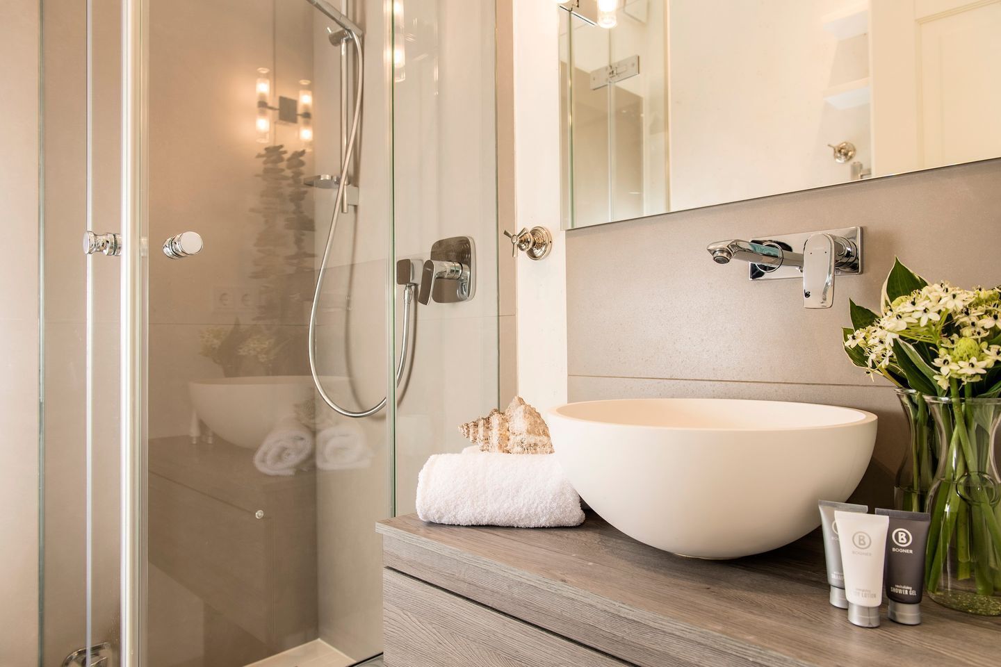 A modern bathroom with a glass shower enclosure, a large vessel sink, and a mirror above the vanity.