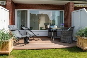 Una terrazza con due poltrone, un tavolo e piante in vaso.