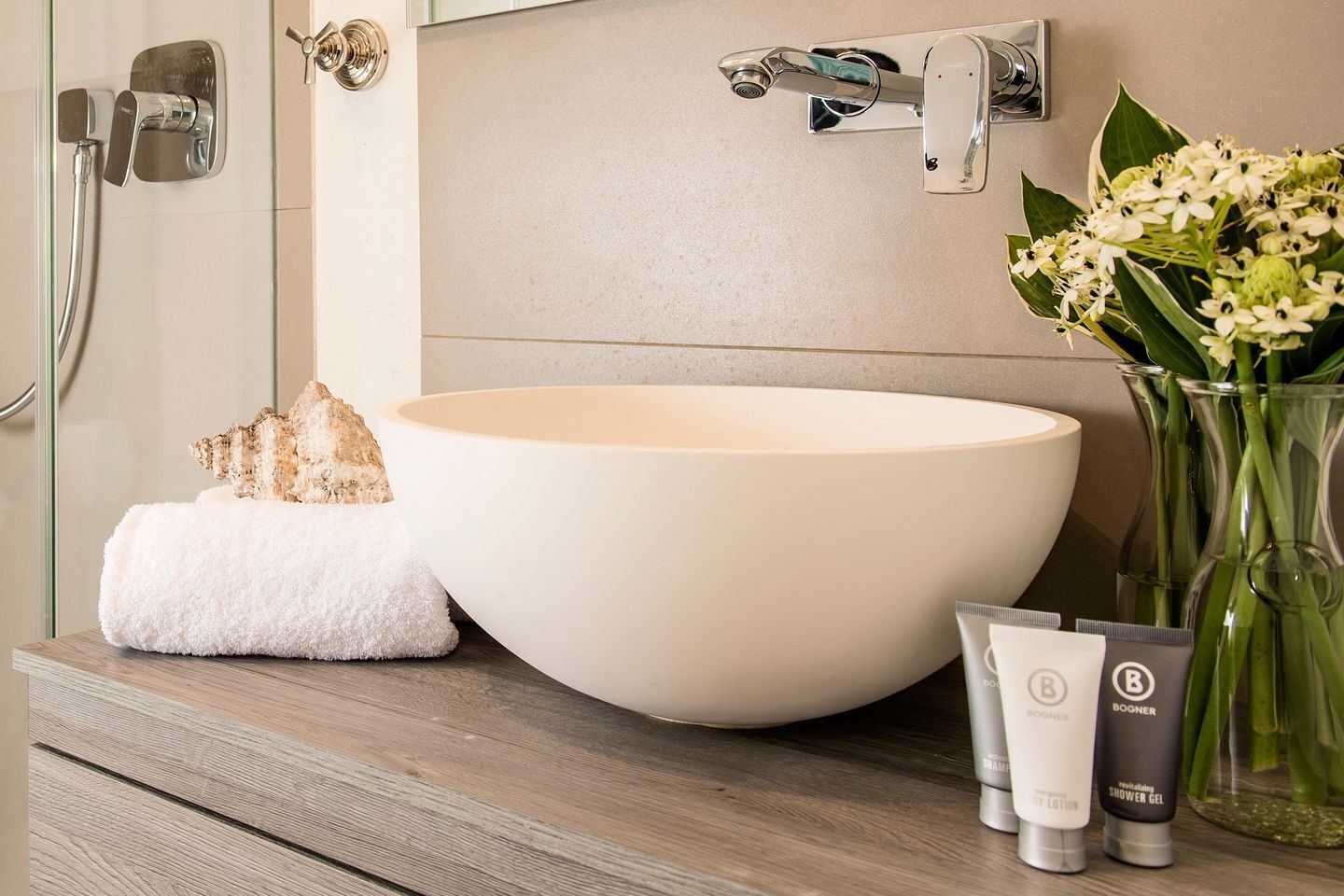 A bathroom with a large white basin, a towel, and toiletries on the counter.
