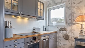 A modern kitchen with grey cabinets, a built-in oven, a dishwasher, and a window above the sink. - Inselliebe, App. 18 - Inselliebe Pur! Viel Mehr Sylt-style Können Sie Nicht Buchen (Wenningstedt-Braderup (Sylt))