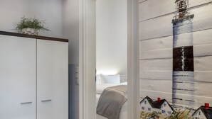 A hotel room with a bed, a wardrobe, and a wall with a painting. - Landhaus Berthin-bleeg, App. 8 Di Füürtoorn - Top Lage. Design-ausstattung. Alles auf Einer Ebene (Wenningstedt-Braderup (Sylt))