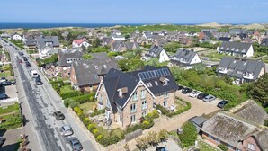 A residential area with houses, a road, and a view of the sea. - Landhaus Berthin-bleeg, App. 8 Di Füürtoorn - Top Lage. Design-ausstattung. Alles auf Einer Ebene (Wenningstedt-Braderup (Sylt))
