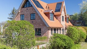 Una casa espaiosa de dos pisos amb un teulat pronunciat, diverses finestres i façana de maó.