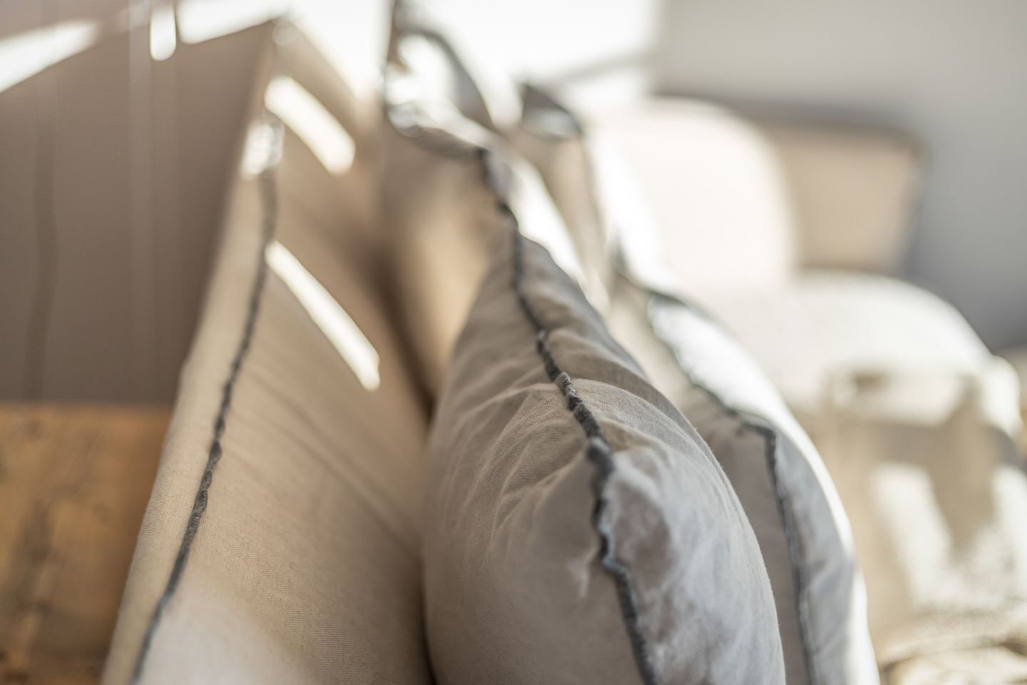 A close-up of a bed with pillows, a wooden headboard, and a blurred background suggesting a room interior.