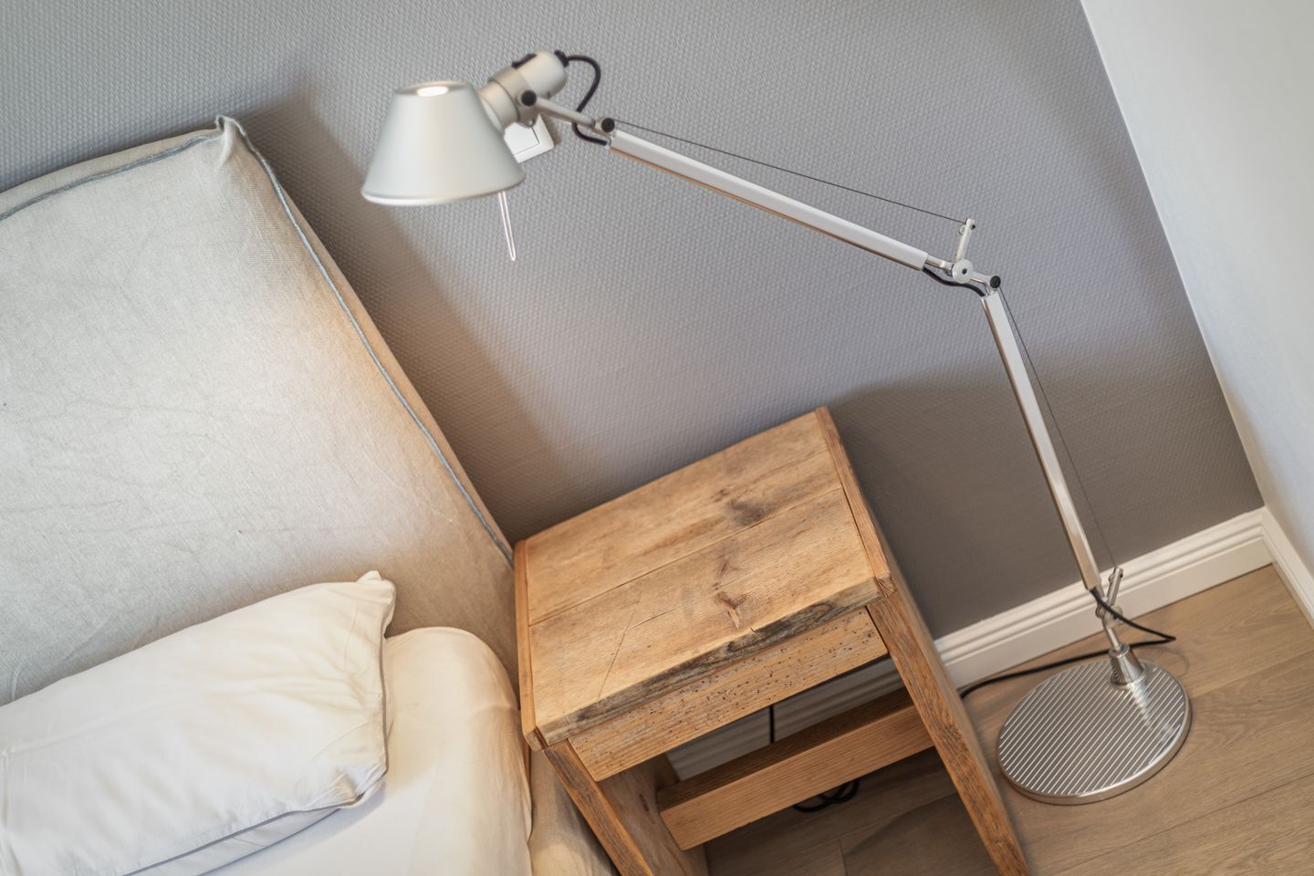 Une pièce comprenant un lit, une petite table de chevet en bois et une lampe sur pied.