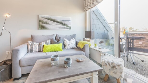 Una sala de estar moderna con un sofá gris, una mesa de centro y un ventanal con vistas al exterior.