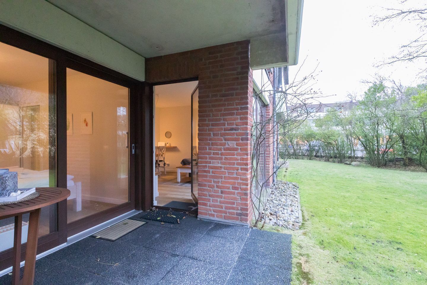 Un edificio residenziale con una porta in vetro che dà su una stanza con una sedia e un tavolo.