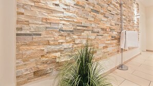A bathroom with a stone wall, a floor lamp, and a potted plant. - Landhaus Berthin-bleeg, App. 7 Lichtblick OG Rechts - Zwei Raum Appartement im 1. OG auf Einer Ebene (Wenningstedt-Braderup (Sylt))