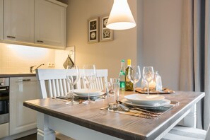 A dining area with a wooden table set for two, featuring wine glasses, a bottle of wine, and a candle. - Landhaus Berthin-bleeg, App. 7 Lichtblick OG Rechts - Zwei Raum Appartement im 1. OG auf Einer Ebene (Wenningstedt-Braderup (Sylt))