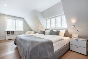 Un dormitorio moderno con una cama grande, dos mesitas de noche y un ventilador de techo.