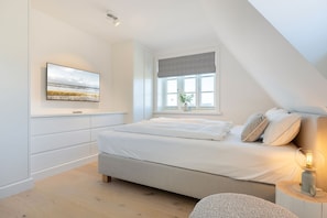 A modern bedroom with a large bed, a window with a view, and a painting on the wall. - Liv Hûs - Dieses, Unter Reet Gebaute, Neue Hausteil in Strandnähe Bietet Platz auf 200 qm (Wenningstedt-Braderup (Sylt))